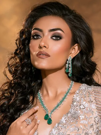 An elegant beauty portrait where the pose and lighting draw attention to the delicate emerald necklace and the model's sculpted features.