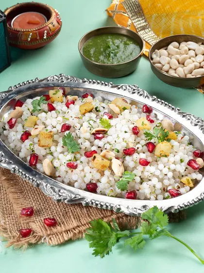 This festive presentation of Sabudana Khichdi uses traditional silver serveware and bright props to suit a Navratri or other festival-themed menu.