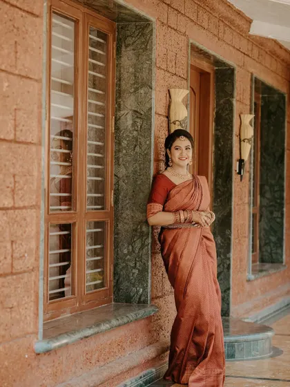 A full-length shot of the bride-to-be, looking serene and beautiful. The simplicity of her makeup and the classic drape of her saree create a timeless and elegant picture.