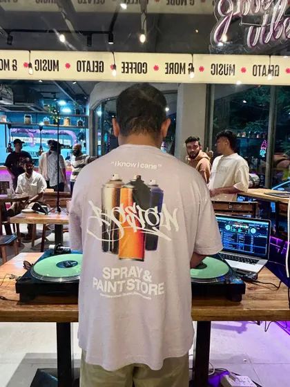 A view from behind the decks at a cafe gig. My shirt says "Spray & Paint Store," a nod to my love for hip-hop and graffiti culture.