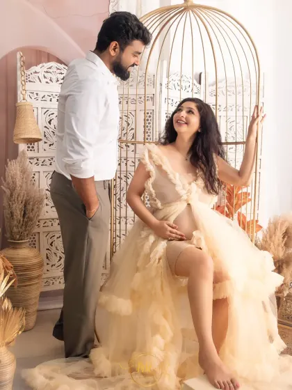This shot showcases one of my popular studio setups, featuring a golden birdcage chair, pampas grass, and a carved white screen for a stylish boho maternity portrait.