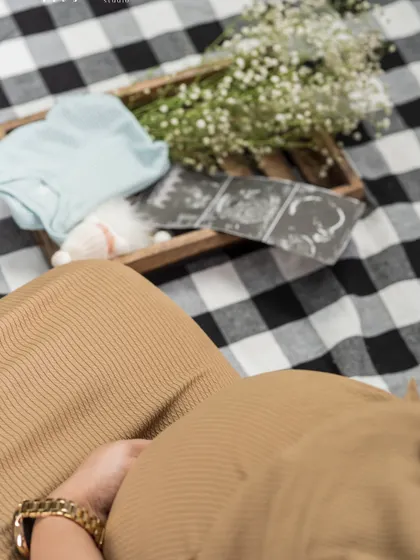 A creative flat-lay shot, showing the baby bump alongside ultrasound photos and a tiny baby outfit. It's a beautiful way to tell the story of anticipation.