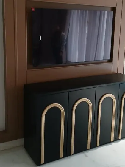 This striking black TV console features arched, gold-tone details on its four doors. The bold contrast and art-deco-inspired design make it a glamorous and sophisticated addition to any entertainment area.