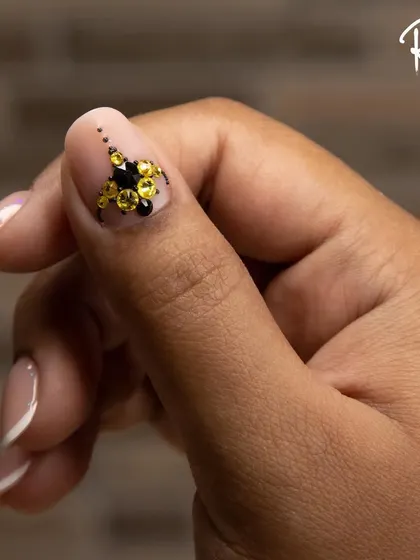 A close-up of a French manicure with a striking black and yellow crystal cluster. This is a great example of how to add a bold, modern twist to a classic style.