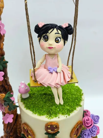 A close-up of a delicate fairy figurine sitting on a swing. I'll show you how to create serene facial expressions and flowing dresses for magical, fairytale-themed cakes.