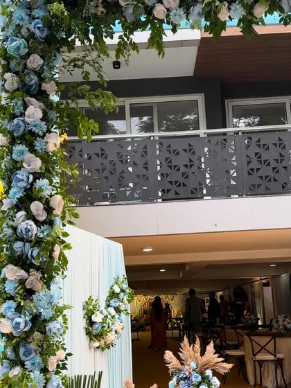 A wide view of the entrance to the Sai Sandhya, where a large floral arch in shades of blue and white welcomes guests into the serene space.