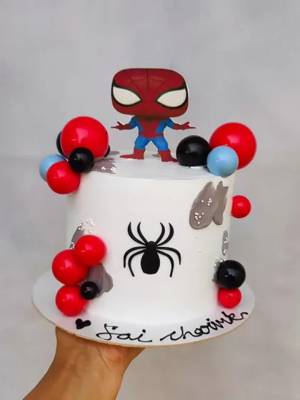 A fun Spiderman cake featuring a pop-figure style topper. I used red and black chocolate spheres and the iconic spider logo to complete this superhero design.