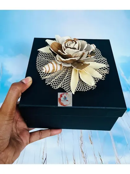 The exterior of our elegant black gift box, topped with a beautiful handmade paper flower decoration.