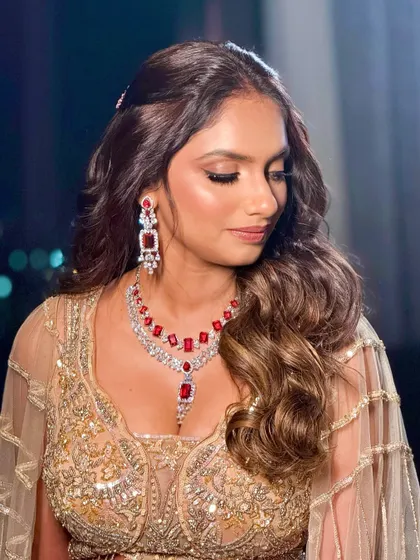 A glamorous reception look with a bold red ruby necklace and a golden, shimmering gown.