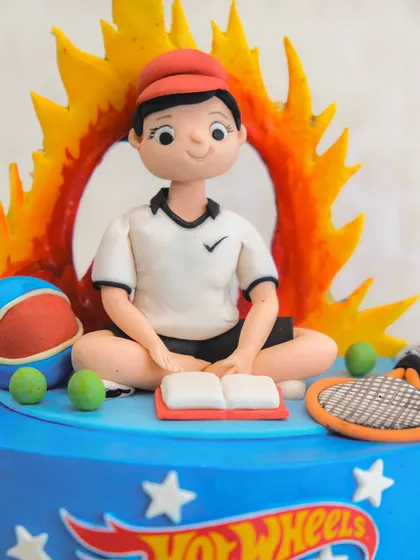 A cake full of fun! This topper shows a character who loves reading, basketball, and tennis, all surrounded by a Hot Wheels theme.