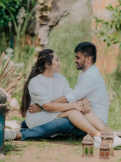 A sweet moment of the couple sitting together in a garden setting. The lanterns in the foreground add a charming, decorative element to the scene.