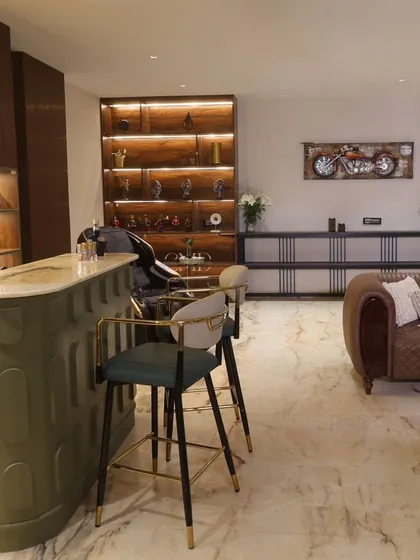 A close-up of the sleek, PU-finished bar counter with a CNC design, paired with stylish bar chairs that complete the luxurious look of this entertainment space.