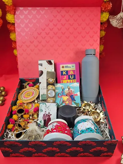 A grand Diwali hamper for a special celebration. This box is filled with a mix of everything: a speaker, mugs, a water bottle, snacks, and traditional decor items.