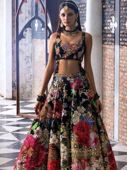 A bold and beautiful black floral lehenga. The intricate, multi-colored floral embroidery stands out against the black base, making it a stunning choice for an evening wedding event.