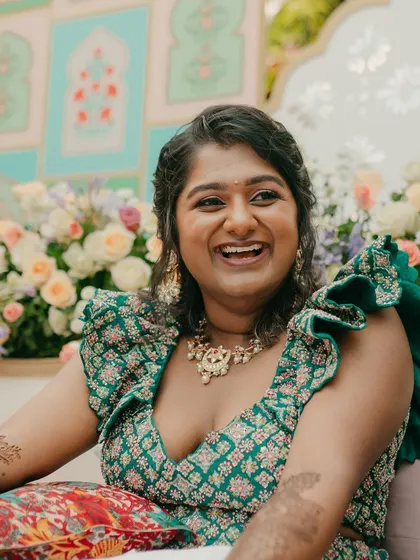 The bride's radiant smile as she gets her Mehendi done, seated in front of the beautiful pastel backdrop.