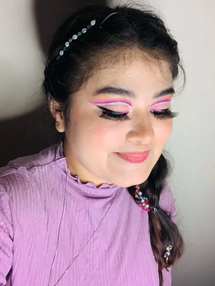 An angelic, fantasy look with purple and white graphic liner, long lashes, and beaded hair.
