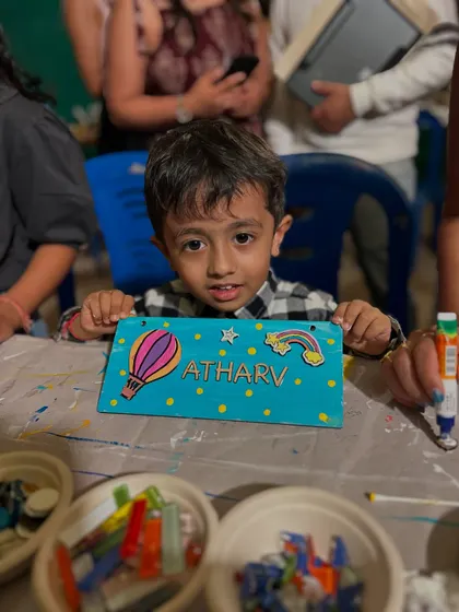A little boy showing off the colorful nameplate he painted at our stall. The hot air balloon is a great touch.