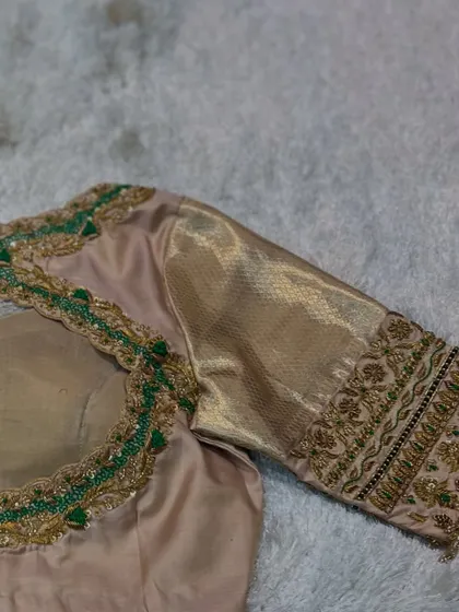 The back of the beige blouse, showing the detailed green beadwork and a simple cut-out.