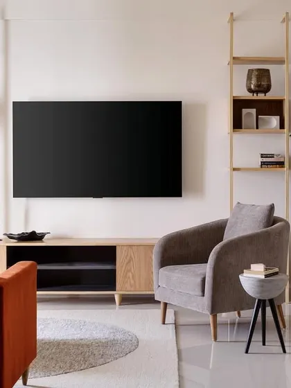 This living room from my 'Soulful Sanctuary' project features a custom open-shelving TV unit that provides ample space for display and storage. The burnt orange sofa adds a pop of color against the neutral, textured brick wall.