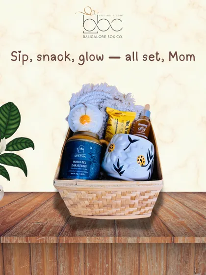 Sip, snack, and glow. This cozy Mother's Day hamper is perfect for helping mom relax and unwind, featuring artisanal tea, a cute mug, and other pampering treats in a lovely bamboo basket.