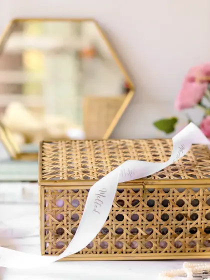 This shot focuses on the elegant, woven exterior of a gift box, with a branded ribbon draped artfully across it. The blurred background keeps the attention on the beautiful and sustainable packaging.