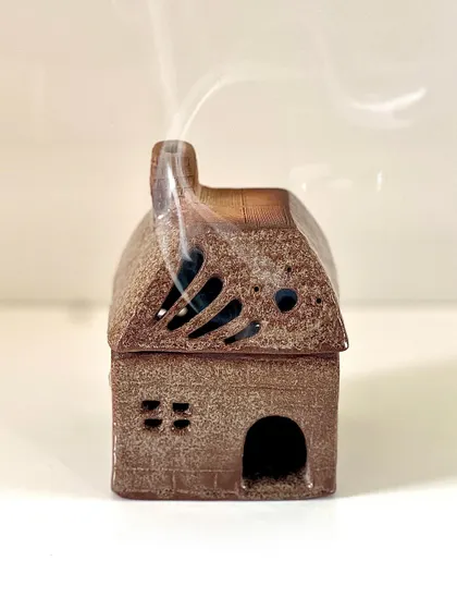 A student's finished house-shaped incense burner, with smoke gently rising from the chimney. A truly charming and functional piece of art.