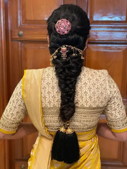 A beautiful fishtail braid accessorized with a statement hairpiece and a traditional kunjalam at the end. This is a perfect blend of modern and traditional styling.