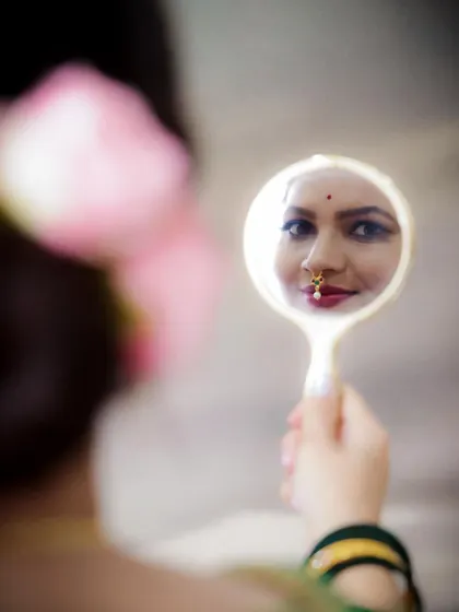 A beautiful and introspective close-up. This shot captures the mother-to-be in traditional attire, reflecting on her journey in a hand mirror. It’s the small, quiet moments that are so powerful.