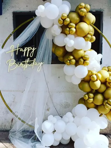A white and gold balloon ring with a sheer white drape for an ethereal and elegant birthday setup.