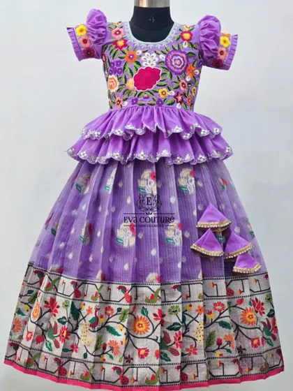 An exquisite lavender lehenga with a floral Paithani-style border. The outfit is elevated by a ruffled, tiered peplum top and a blouse with heavy multi-color floral embroidery.