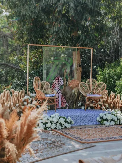 A wider view of the jungle-themed jaimala stage. Set against a backdrop of lush trees, the cane chairs and tiger print create a bold and unforgettable setting for the couple.