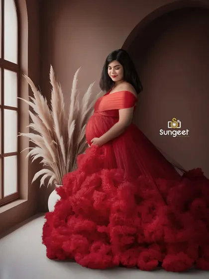 The rich red of this ruffled gown looks stunning against the warm, earthy brown backdrop. The window light adds a soft, natural feel.