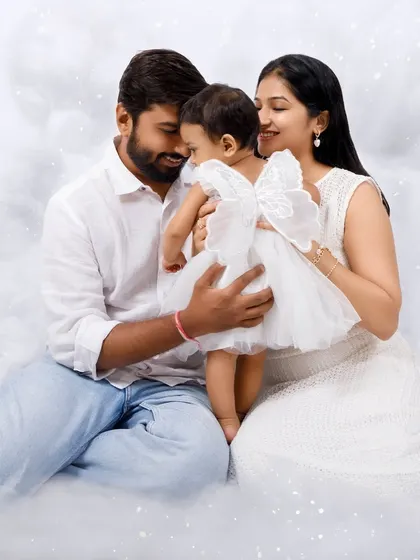 A beautiful family portrait in the clouds. The parents embrace their little angel in this dreamy, all-white setup.