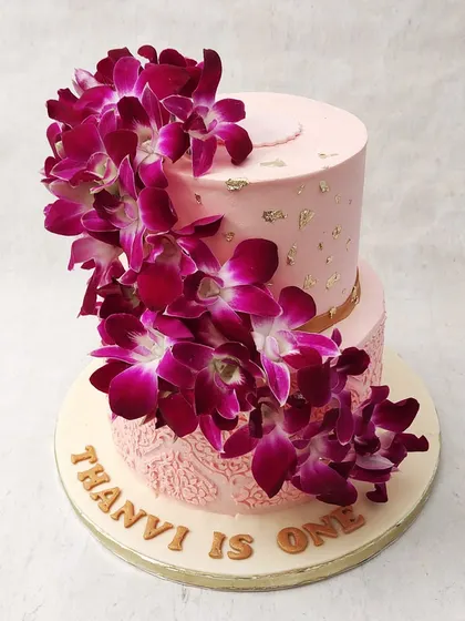 We make a bold and beautiful statement with this two-tiered orchid cake. A dramatic cascade of fresh, deep magenta orchids flows down the side of the soft pink tiers, creating a stunning visual contrast that is both luxurious and exotic.
