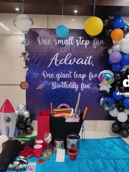 An out-of-this-world space theme for a 5th birthday. The setup includes a galaxy backdrop, planet cutouts, a rocket, and a light-up number '5', ready for an astronomical amount of fun.
