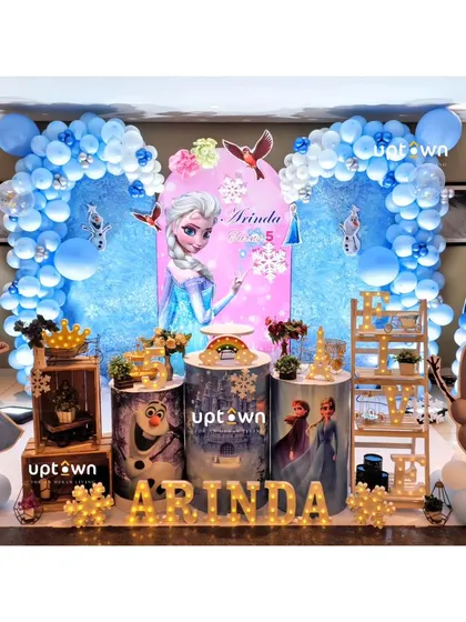 A full stage setup for a Frozen themed 5th birthday, featuring multiple character props and a winter wonderland backdrop.