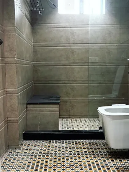 This bathroom features a glass partition for the shower area, which keeps the space feeling open. The textured wall tiles contrast nicely with the patterned floor.