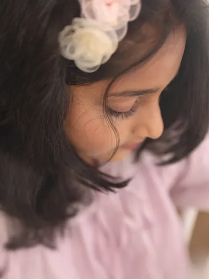 A delicate close-up of the young girl from the reading session. This detailed shot highlights her serene expression and the soft, floral hair accessory.