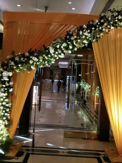 A simple yet elegant entrance arch for a hotel wedding. I used a beautiful orange drape and a semi-arch of fresh white flowers to create a warm and inviting entryway for the guests.