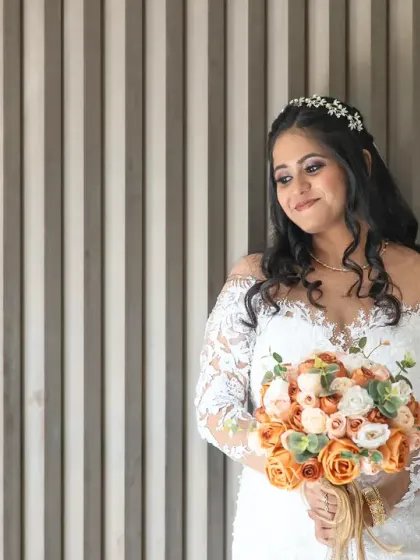 An elegant bridal portrait against a modern, textured wall. The simple background makes the bride and her beautiful bouquet stand out.