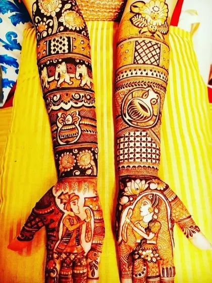 A classic design with the couple in a varmala pose. The arms are filled with traditional motifs like elephants, kalash, and floral patterns.