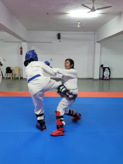A student executes a controlled kick during a Kumite match, demonstrating the importance of technique and control, even in a dynamic exchange.