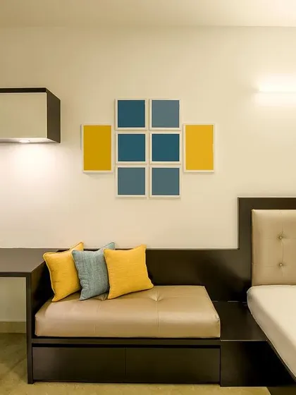 A minimalist yet warm room featuring a built-in sofa and desk unit, with pops of yellow and blue in the decor to add a touch of playful color.