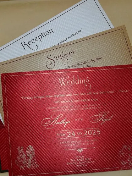 A fan of inserts in red, gold, and cream, showing the variety and richness of a complete wedding stationery suite.