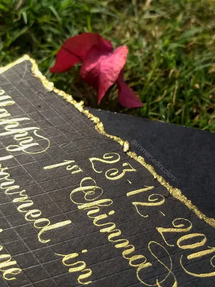 Another detail shot of a custom anniversary letter, highlighting the date and the beautiful shimmer of the golden ink on the textured black cardstock.
