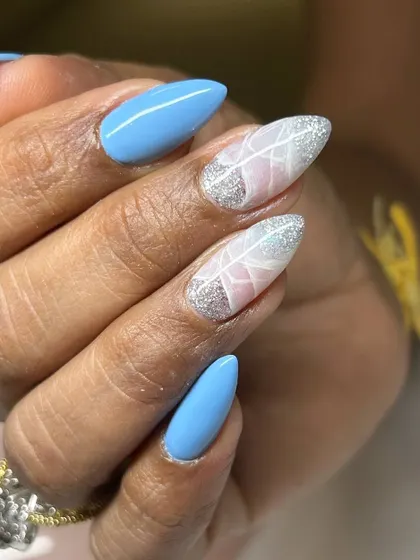 A beautiful and delicate nail art design. This set features a bright blue base with two accent nails showcasing a white feather design over a sparkling silver and pink background.