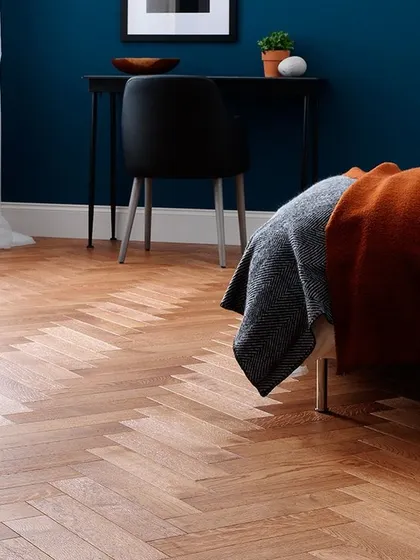 The herringbone pattern is a timeless classic that I love to install. In this bedroom, the light wood in a herringbone layout adds texture and a sense of luxury without overwhelming the space.