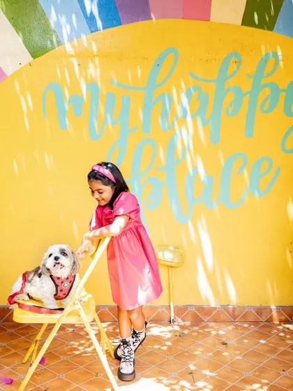 We found the perfect spot for this photo at a local cafe. The "my happy place" wall mural was a colorful and fitting backdrop for this spunky girl and her adorable dog.