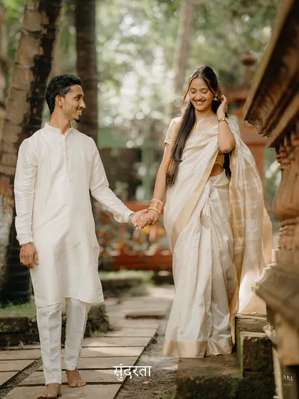 Sundarta in simplicity. A candid moment of the couple walking hand-in-hand through a rustic, natural path, their traditional white outfits creating a serene and beautiful picture.
