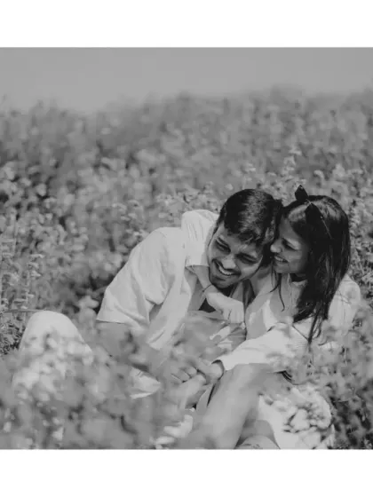 An intimate black and white shot of the couple sharing a laugh while sitting in the field. This image strips away color to focus purely on the emotion and joy of the moment.